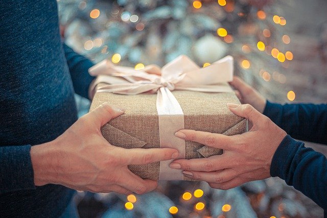 Muž a žena spolu v rukách držia zabalený darček.jpg