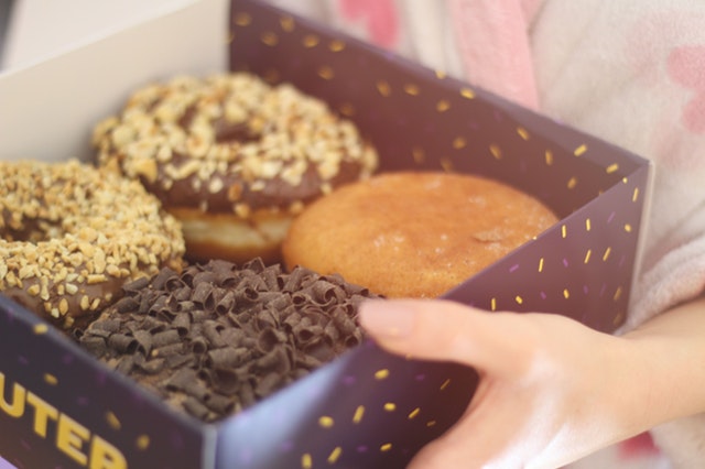 Žena nesie krabicu so sladkými donutmi.jpg